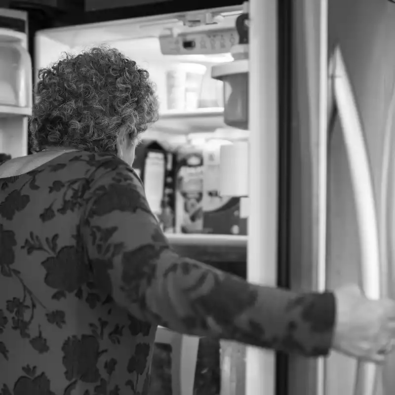 Elderly woman opening refrigerator