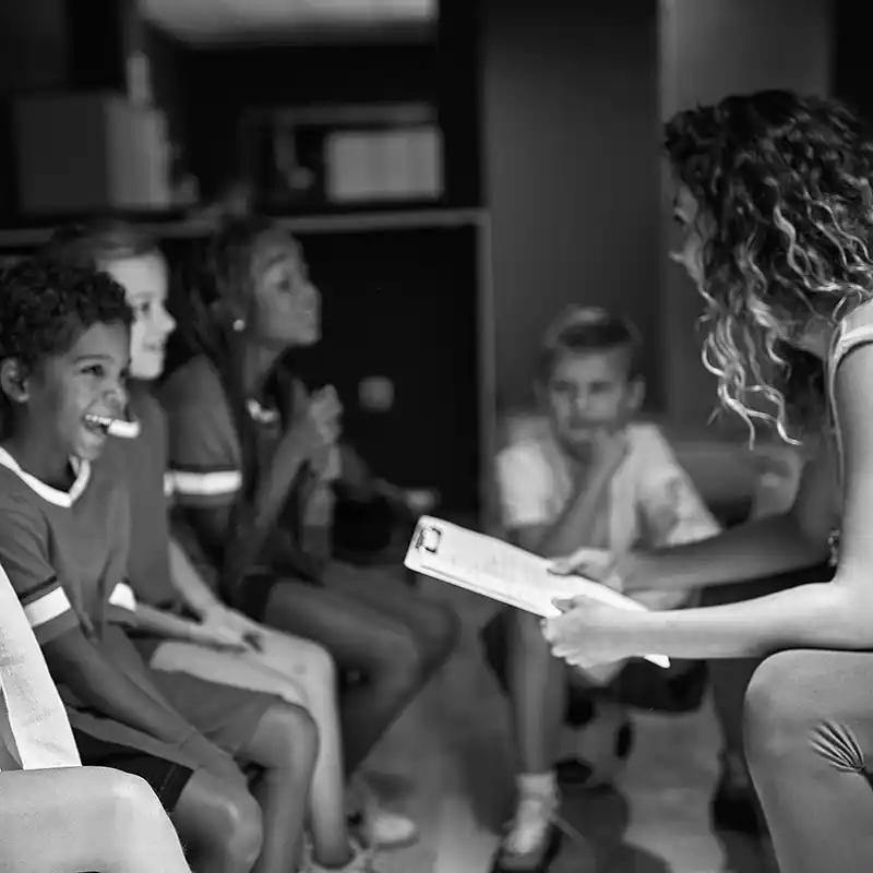 Sports coach talking to children in locker room